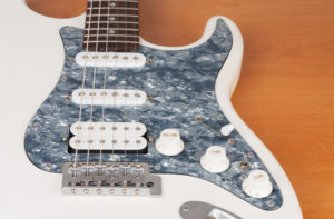 Part of white electric guitar, studio shoot. 2 x Single Coil and 1 x Humbucking. Black Pearl pickguard, Rosewood Fingerboard